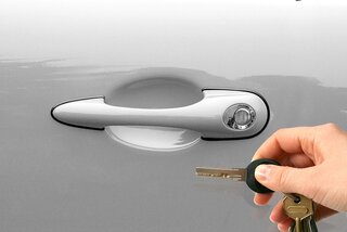 silver car door and hand holding key