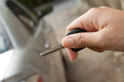 Hand holding key in front of car