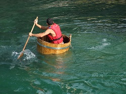 person in a tub rowing in a river