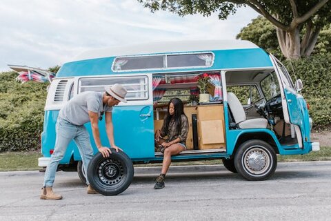 woman on campervan and man with wheel