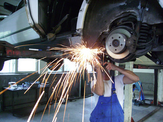 mechanic welding the underside of a car