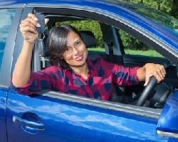 Young person sitting in a blue car holding the keys out the window