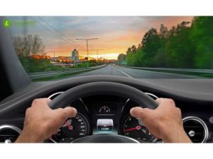 driving into sunset with hands on steering wheel